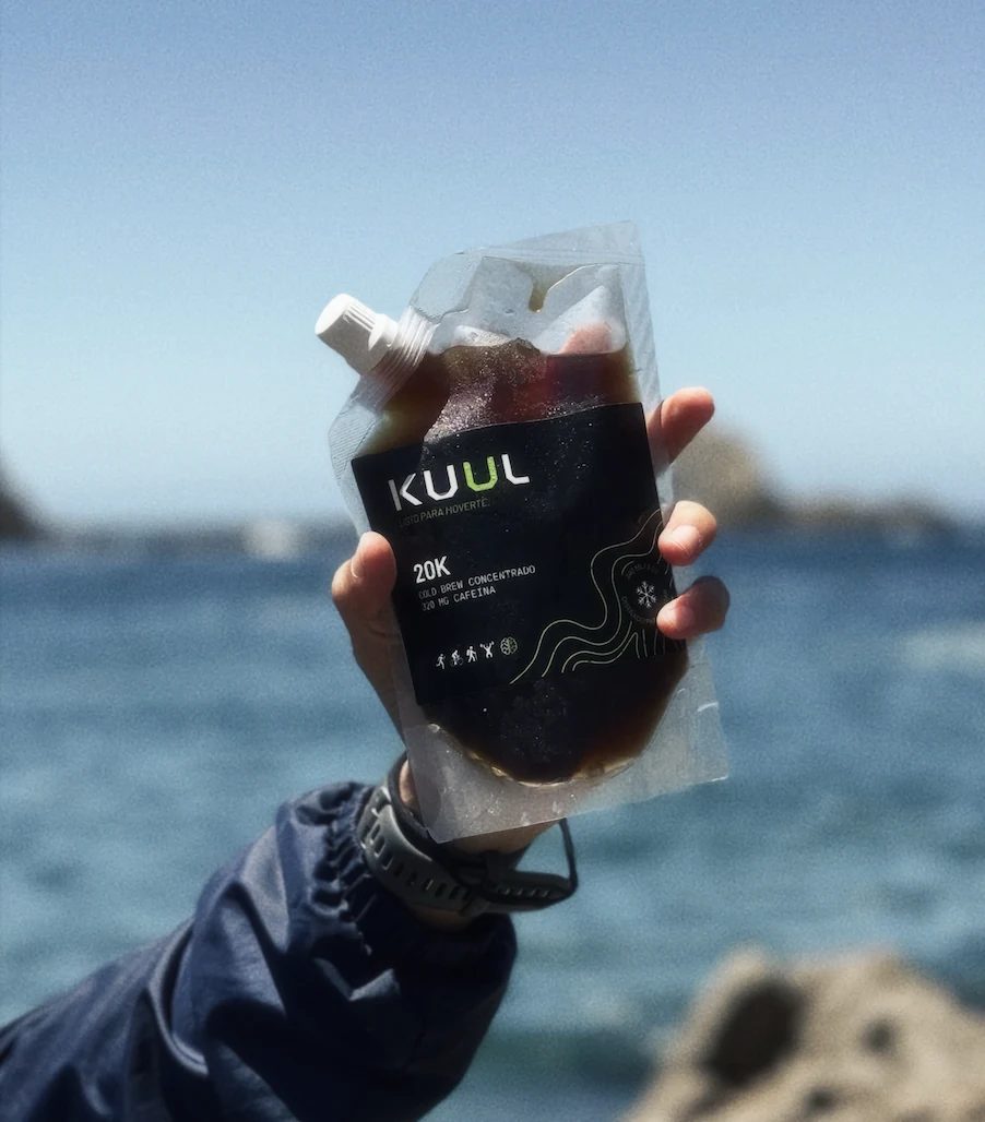 Mano sosteniendo un pouch KUUL frente al mar — filosofía de acción